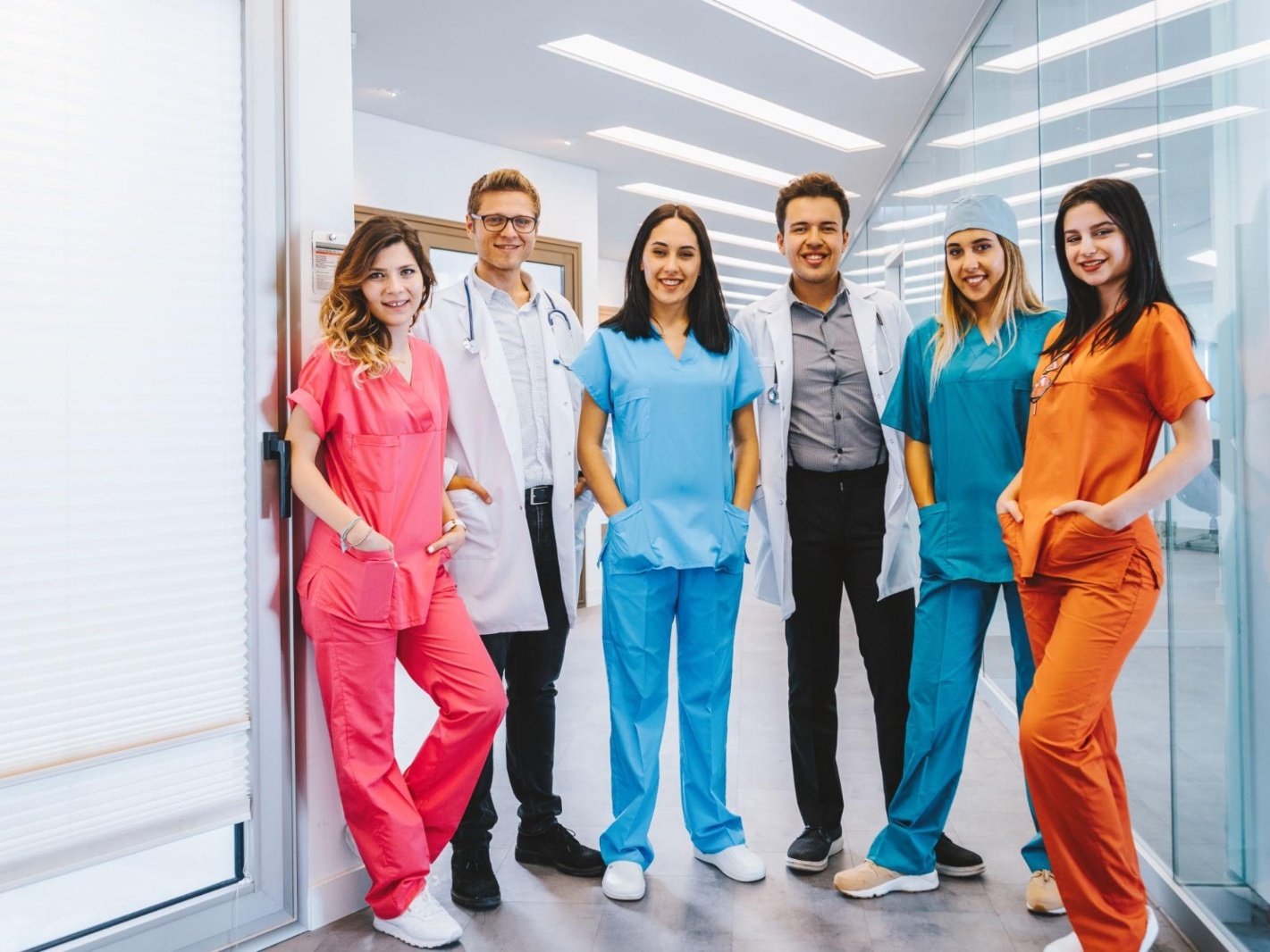 Healthcare and medical team in colourful scrubs and lab coats in a hospital corridor