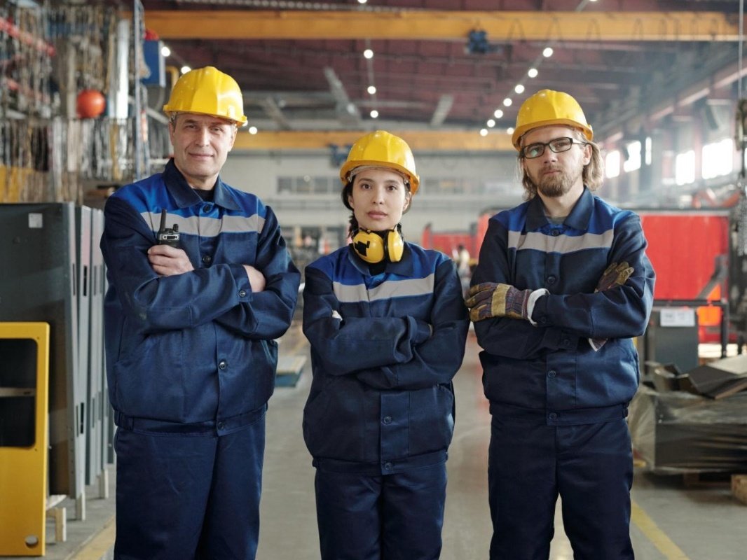 Industrial workers in navy workwear and safety helmets in a factory